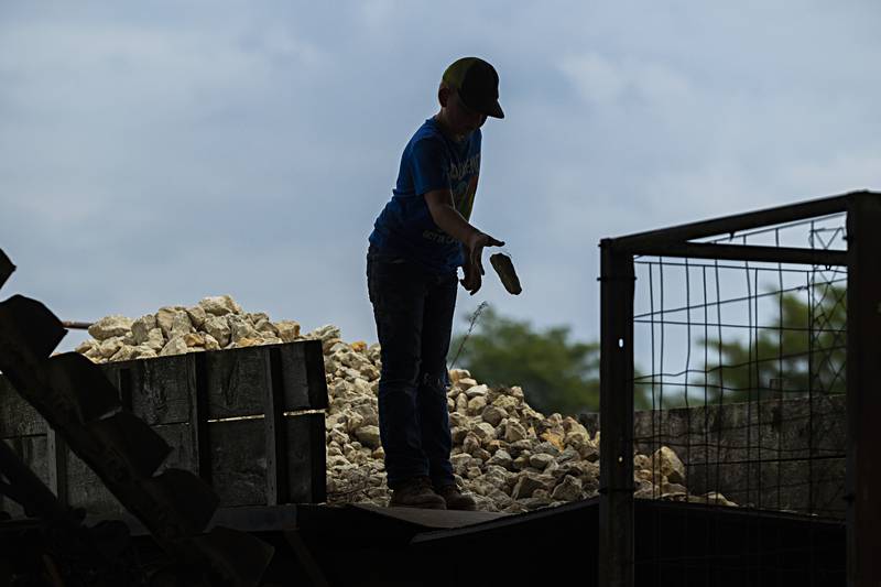 A young man drops rocks into a crusher Saturday, August 5, 2023 at the Living History Antique Equipment Association’s farm show in Franklin Grove.