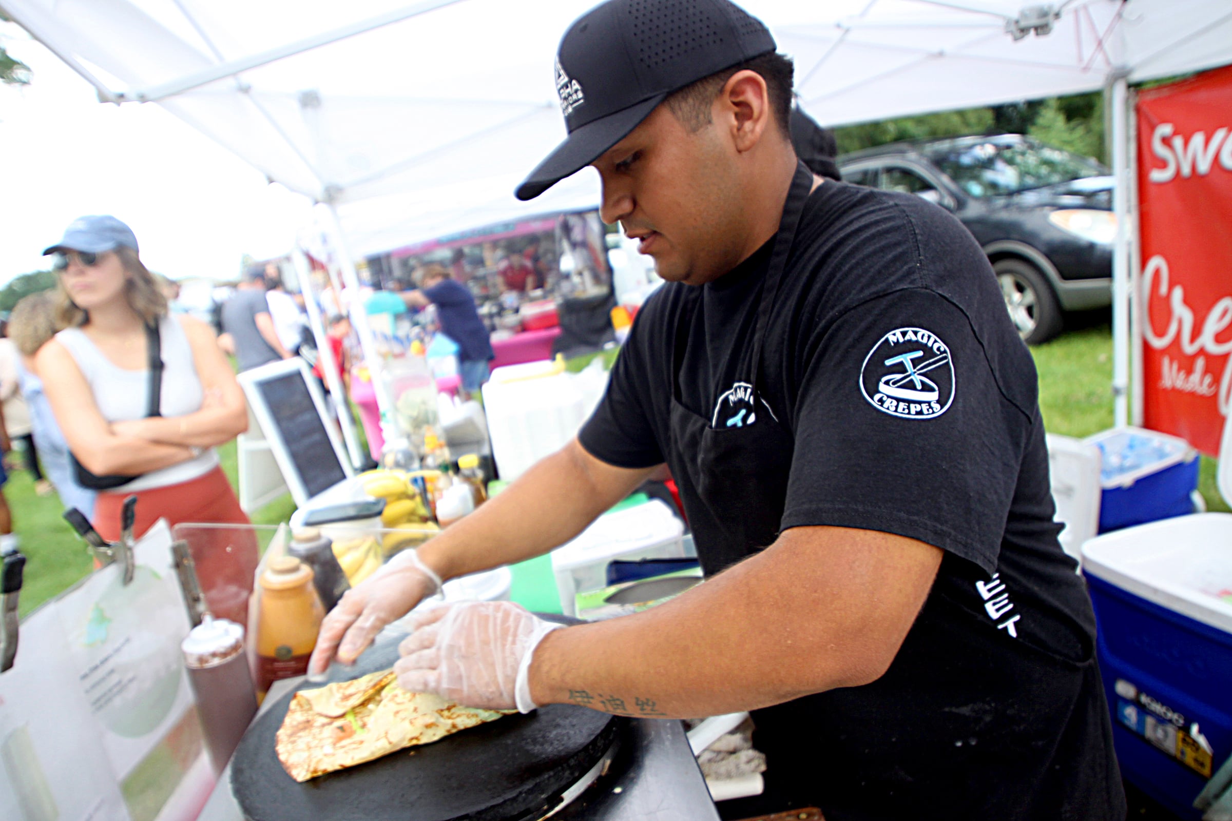 Chef Cris Lopez assembles a crepe at the Magic Crepes booth as part of The Dole Farmers Market in Crystal Lake Sunday.