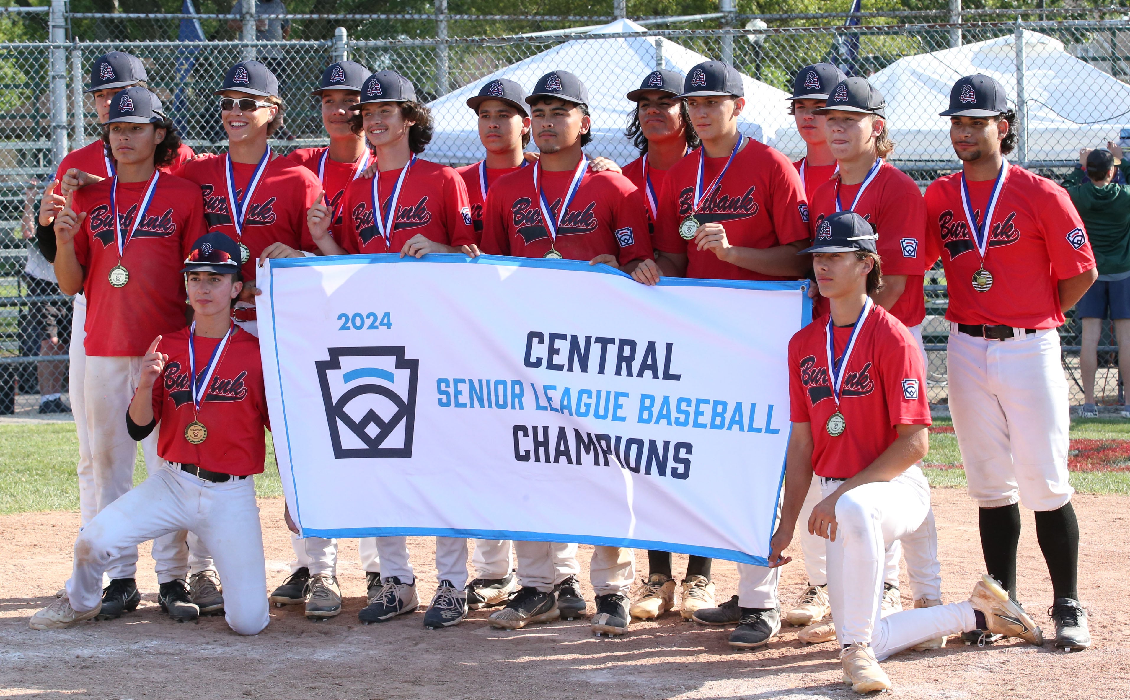 Members of the Burbank Senior League baseball team pose with their banner after defeating Michigan to win the Central Regional Baseball Tournament championship game on Thursday, July 18, 2024 at J.A. Happ Field in Washington Park in Peru.