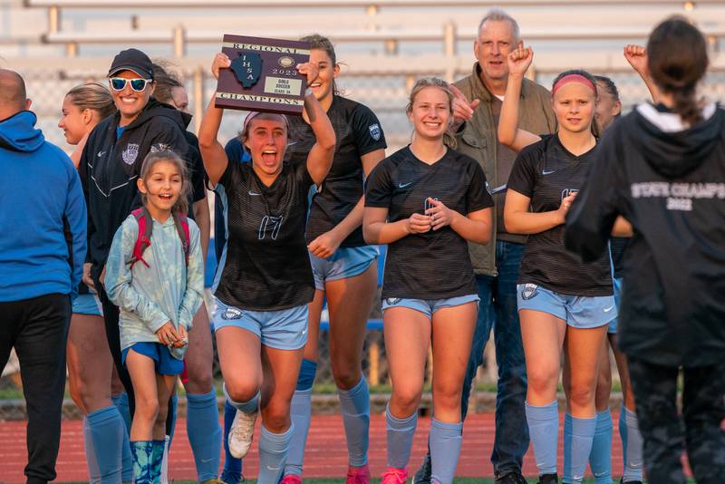 St. Charles North's Bella Najera (17) lifts up the Class 3A regional championship plaque after defeating Wheaton Warrenville South in a Class 3A girls soccer regional final at St. Charles North High School on Friday, May 19, 2023.