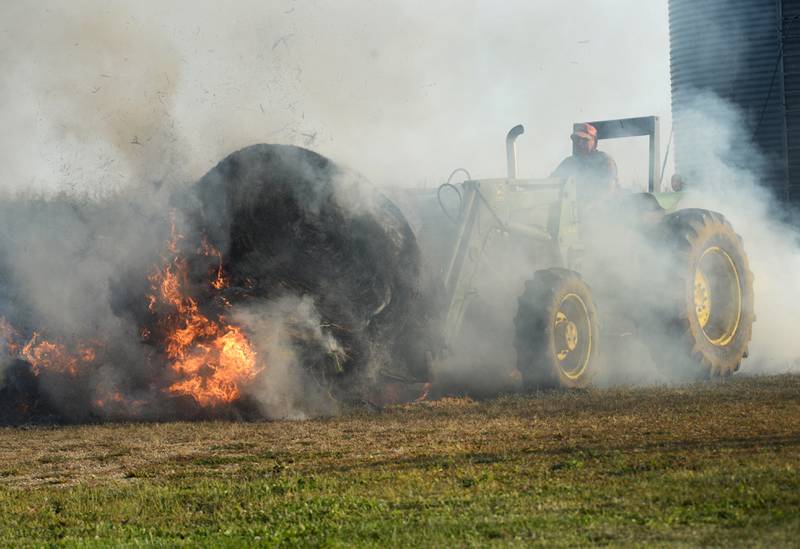 Lyle Hopkins of rural Polo uses a John Deere tractor to move a burning round bale of hay away from a machine shed owned by his neighbor, Herschel Newcomer, during a Monday evening fire at 7015 Judson Road, southeast of Polo on Sept. 10, 2024. Several fire departments assisted the Polo Fire Department on the call. There were no injuries.