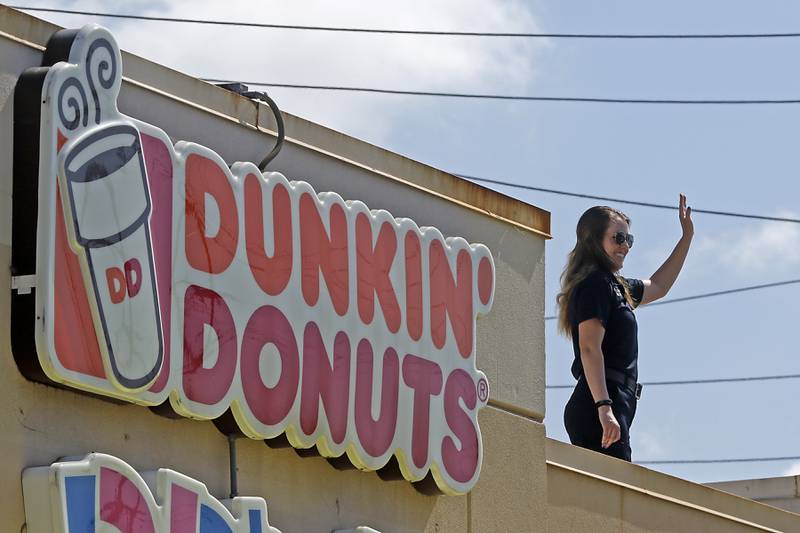 Northeast Regional Communications Center dispatcher Kaitlin Durband waves from the roof during the Cop on a Rooftop fundraiser for Special Olympics Illinois on Friday, May 17, 2024, at 4502 Elm Street in McHenry. Law enforcement officers spent their morning raising funds and awareness for Special Olympics Illinois and the Law Enforcement Torch Run.