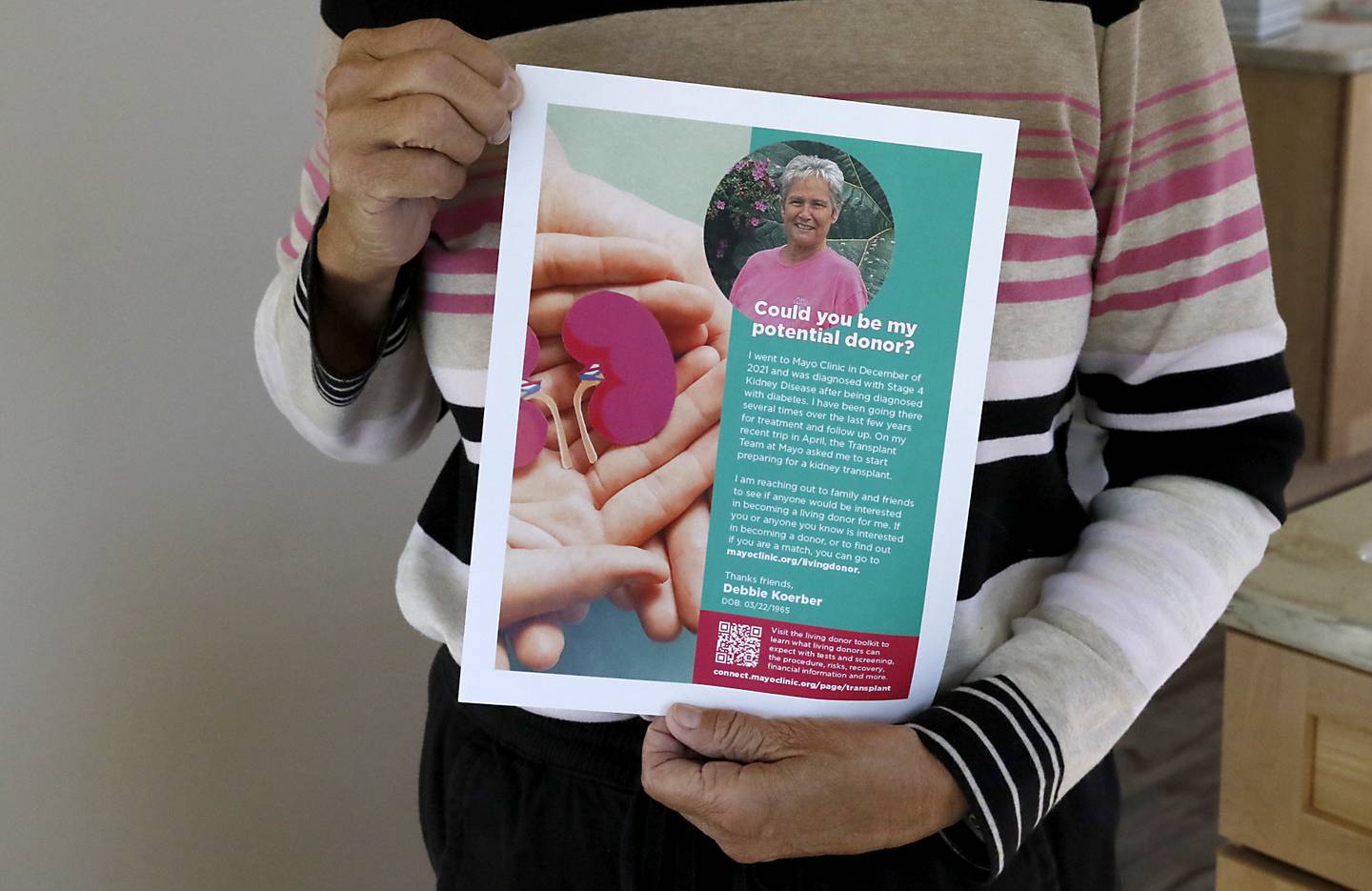 Debbie Koerber holds one of her fliers on Thursday, Oct. 17, 2024, at home in McHenry. Koerber, who will need a kidney transplant one day, has made ads and cards in hopes of finding a donor.