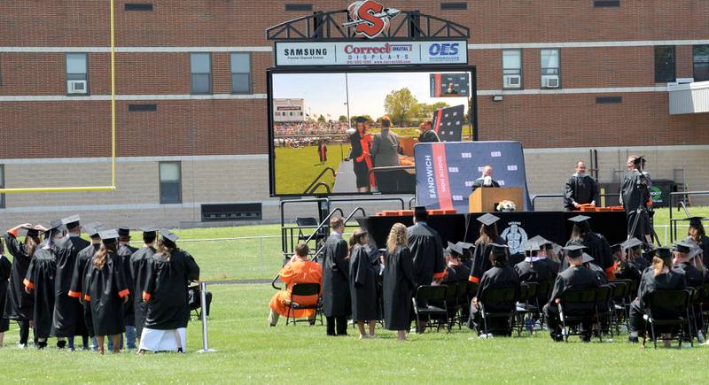 Graduates file across the stage during Sandwich High School's graduation ceremony on the football field, Sunday, May 19, 2024.