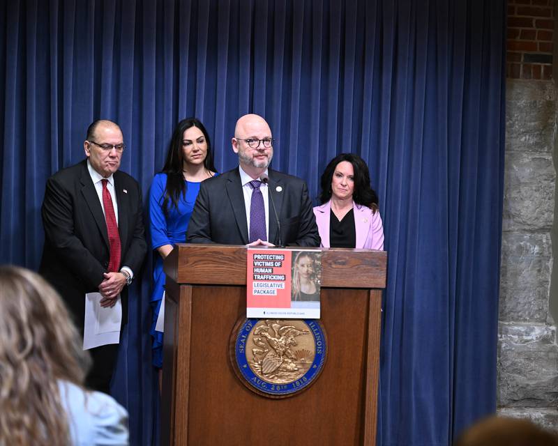 State rep. Jeff Keicher, R-Sycamore, speaks at a podium Thursday, March 7, 2024, flanked by representatives Brad Stephens (left), Nicole La Ha (center) and Jennifer Sanalitro (right) to introduce a package of legislation to combat human trafficking and support victims.