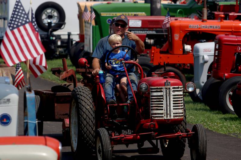 Dennis Storlie of McHenry waits with grandson Wylee, 2, before parking his mid-Fifties International Cub Lowboy  at the McHenry County Fair in Woodstock on Tuesday. Storlie said the tractor was originally purchased by his grandfather.