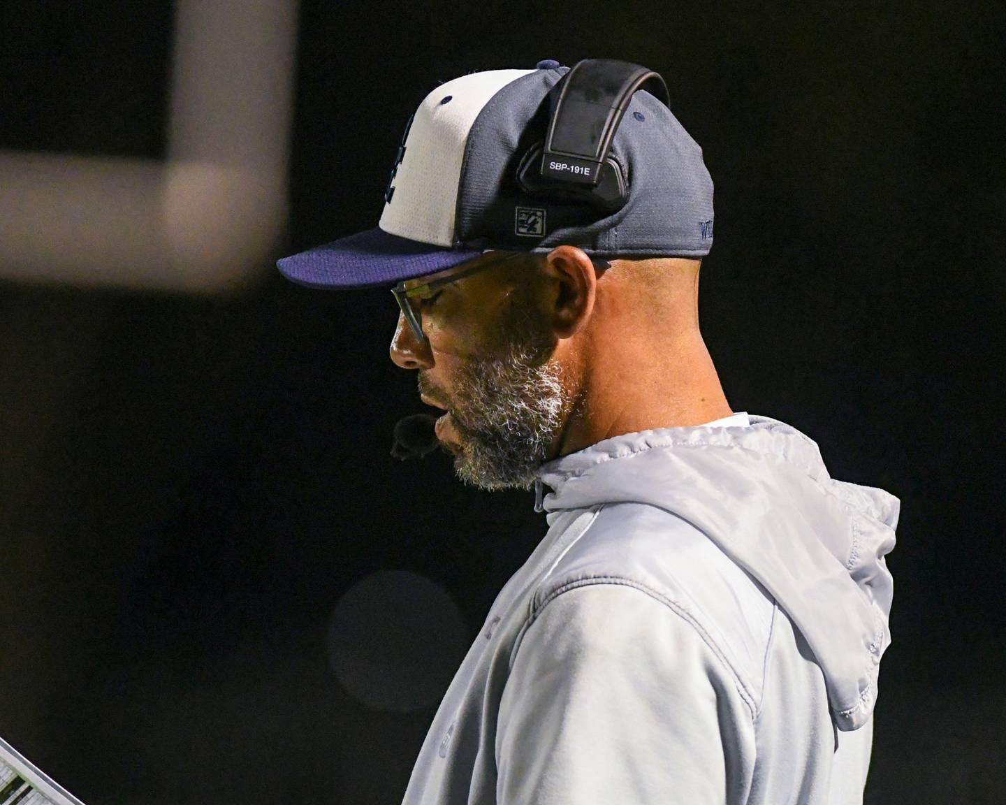 Oswego East's head coach Tyson LeBlanc looks over his plays before the start of a down during the game on Friday Sept. 6, 2024, while traveling to take on Sycamore High School.