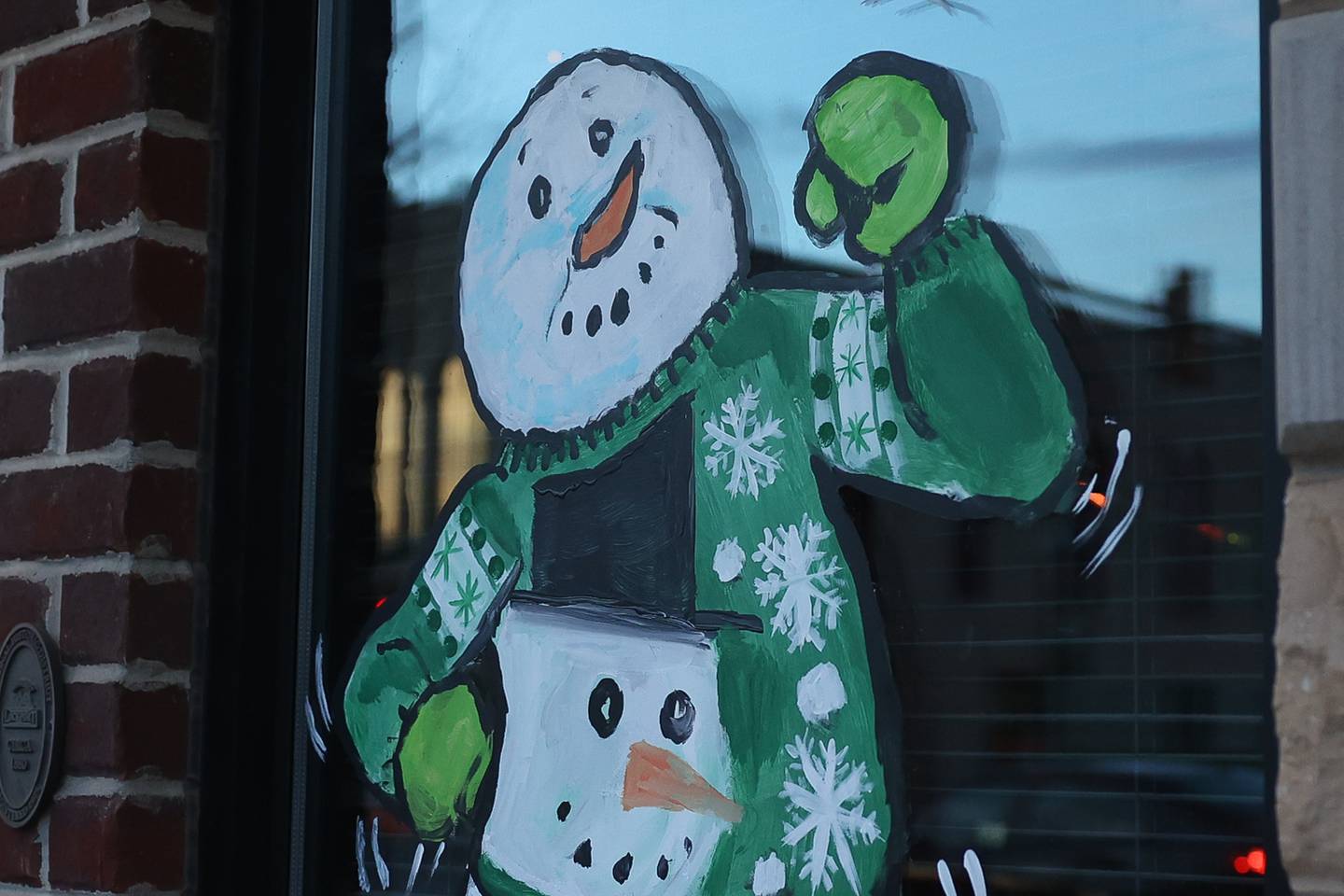 A snowman dons an ugly sweater in the window of Embers Tap House in downtown Lockport on Friday, Dec.15th, 2023. Snowmen decorate the windows of 25 store fronts in downtown Lockport for the holidays.