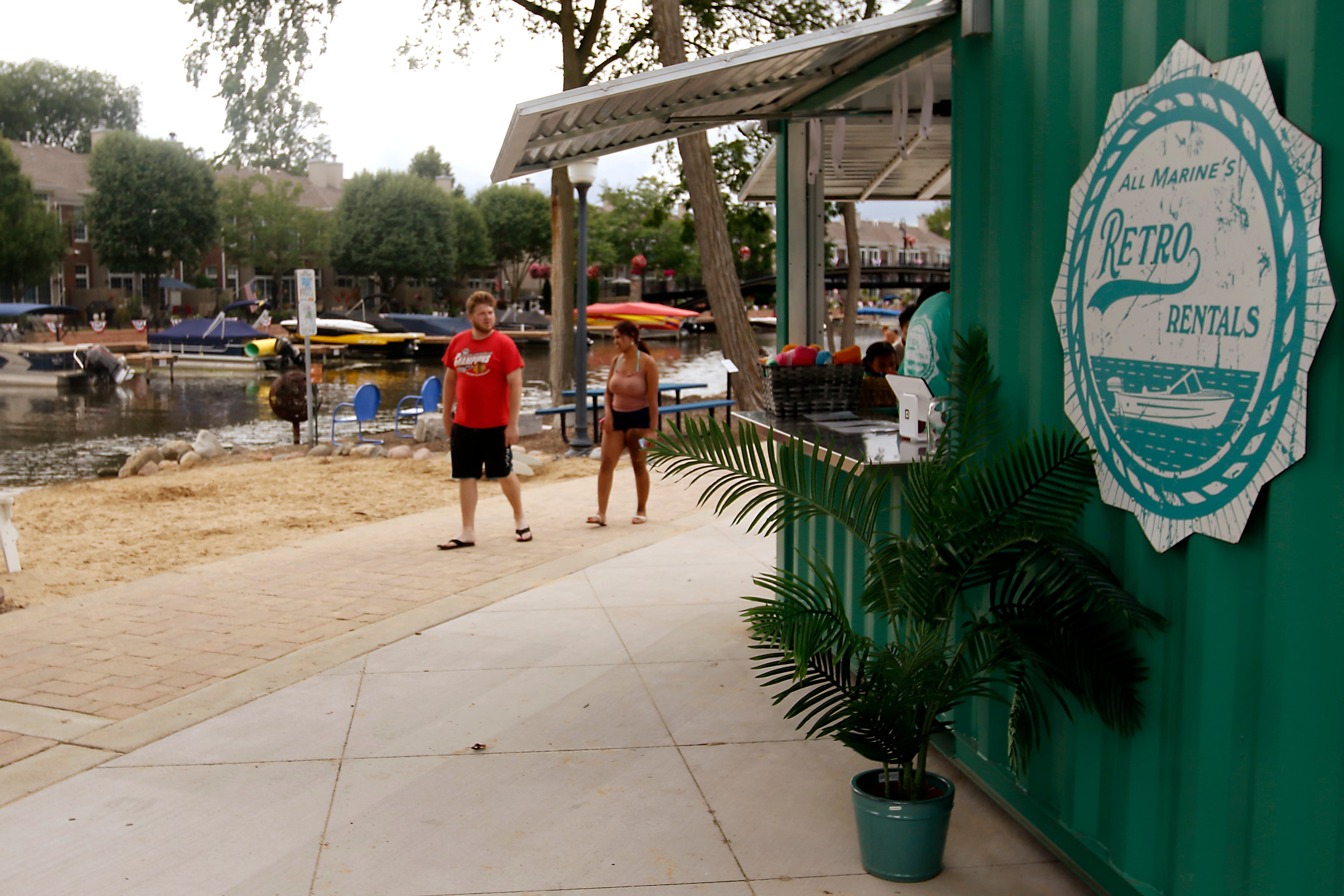 People walk past All Marine’s Retro Rentals and the Retro Retreat Beach Bar in McHenry’s Miller Point Park.