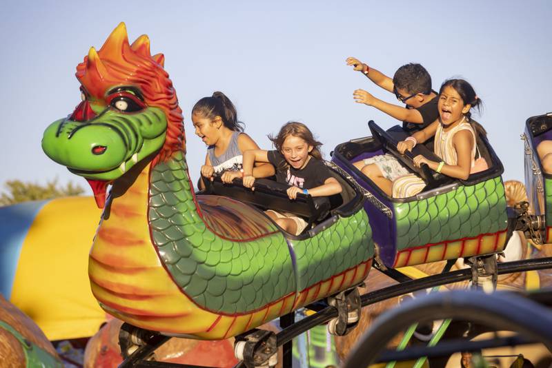 Children scream in excitement as they go around the dragon roller coaster ride at the Mendota Sweet Corn Festival on Friday, Aug. 11, 2023.