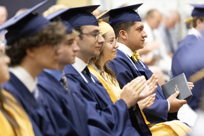 Graduate Katie Hardin joins her classmates in applauding the valedictorian's speech Sunday, May 26, 2024, during Marquette Academy High School's graduation ceremony.