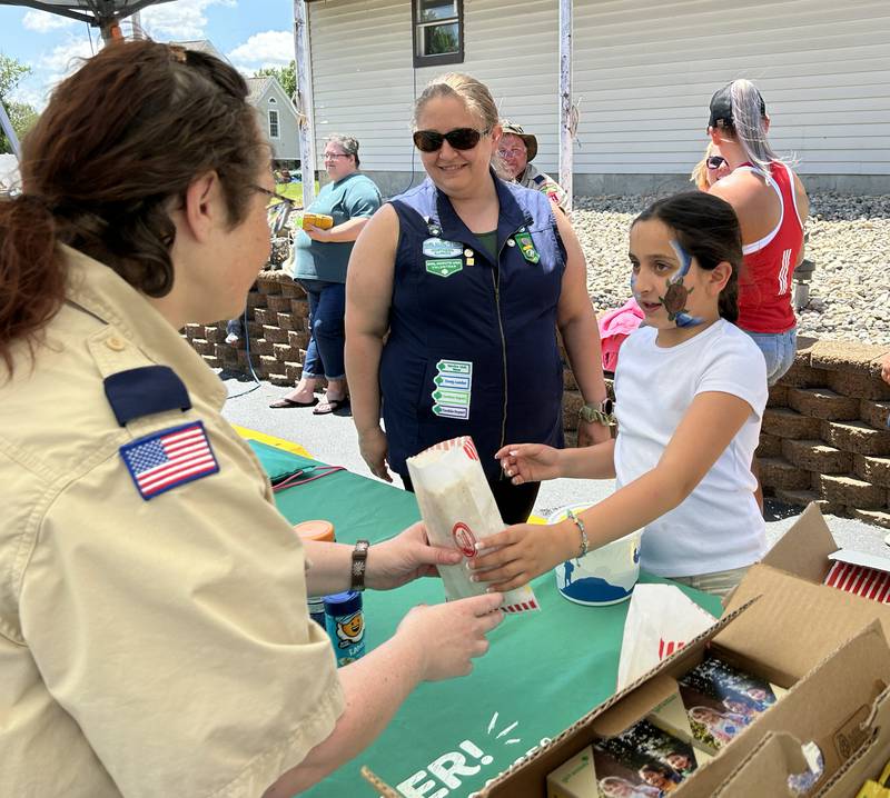 Junior Girl Scout Natalia Nolasco, 9, of Oregon, hands a bag of popcorn to a fellow Scout as Leader Jennifer Robinson watches during the Oregon VFW's Memorial Day family fun event at the Post home in Oregon  on Monday, May 27, 2024.