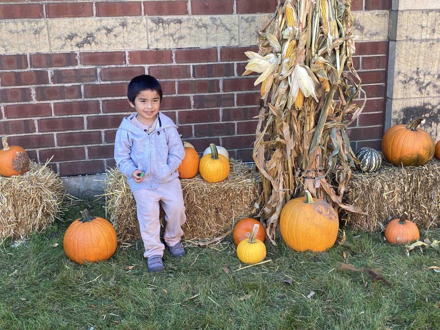 Student Adrian Moreno poses with pumpkins and corn.set up by Will County pumpkin farms at Sator Sanchez Elementary School in Joliet on Friday. Oct. 18, 2024.