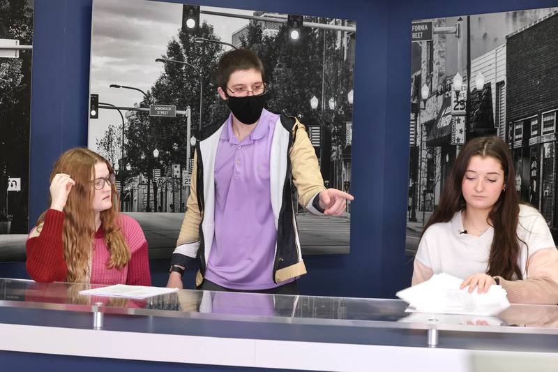 Educator Gregory D'Addario, who teaches TV production and english at Sycamore High School, goes through some script revisions with sophomore anchors Kennedy McCoy, (left) and Hailey Clawson before they tape a news program Wednesday, March 1, 2023, at the school.