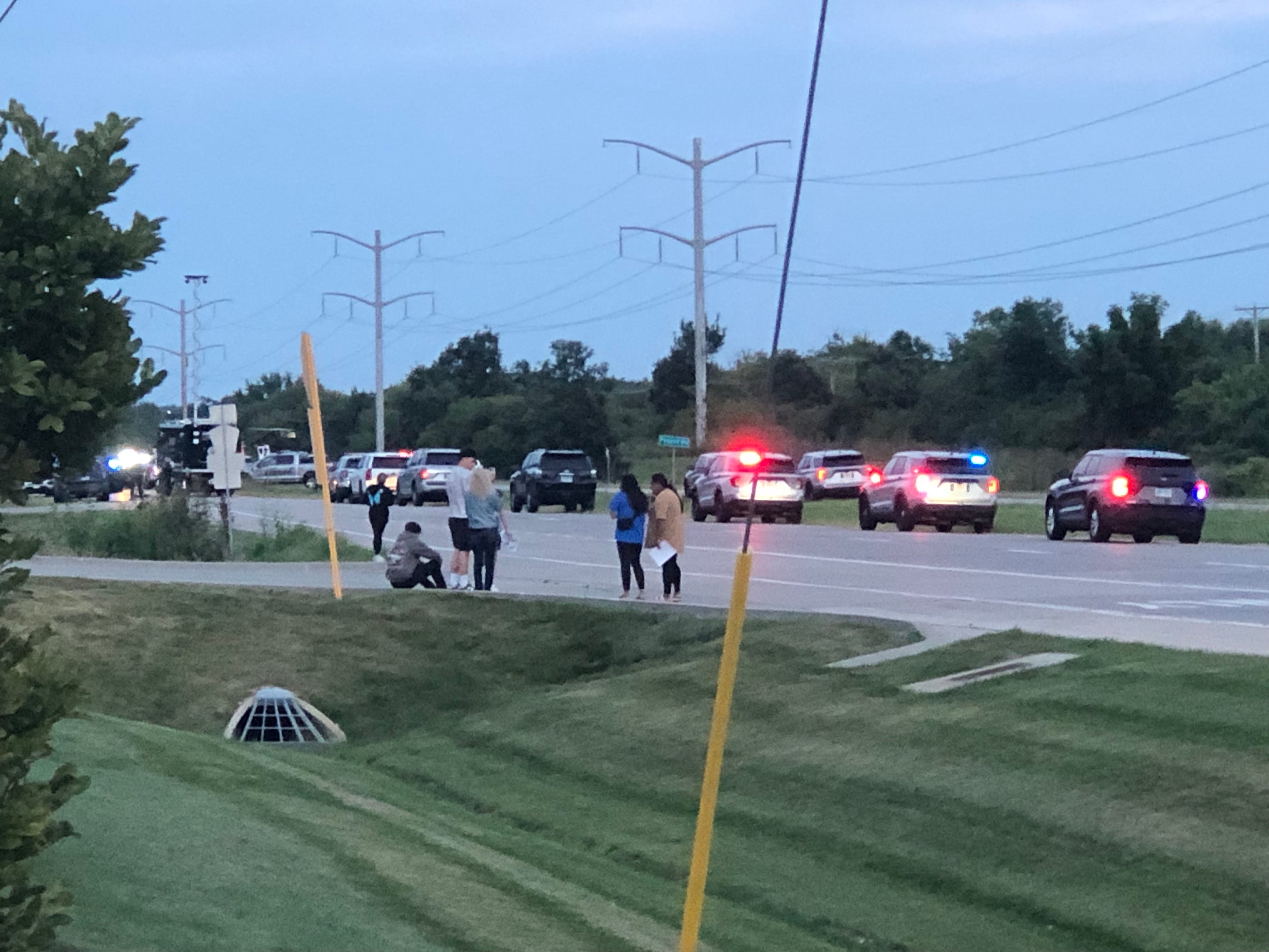 People watch and police are lined up along Route 14 in the Barrington area while a Chicago homicide suspect was barricaded in a nearby building on Aug. 20, 2024, according to authorities. He was taken into custody.