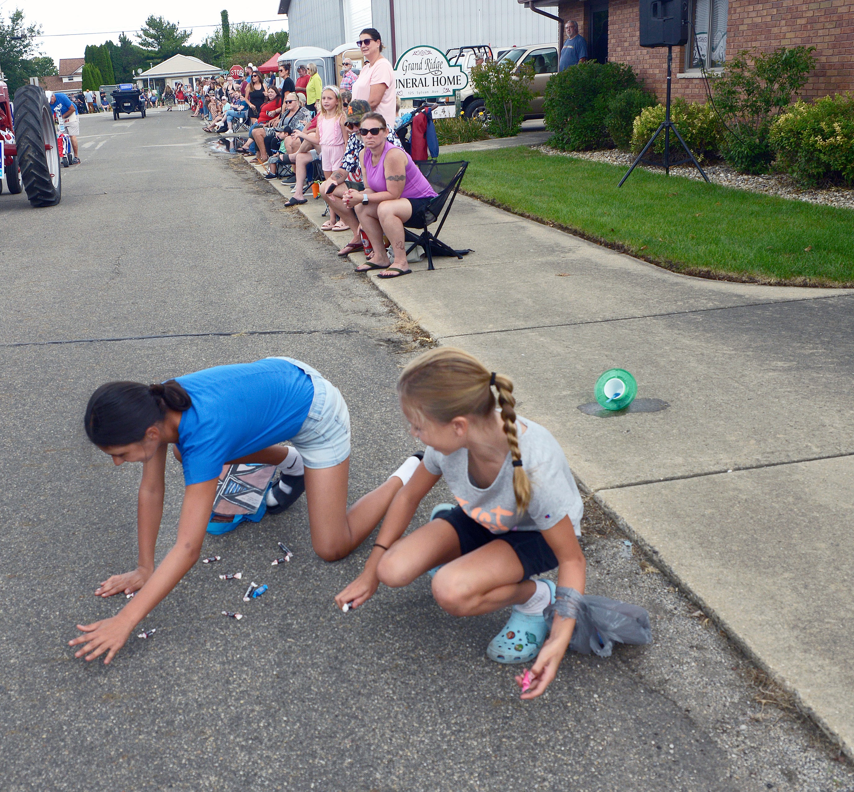 Children along the parade route work to gather candy treats tossed their way during the Community Fest Parade Sunday in Grand Ridge.