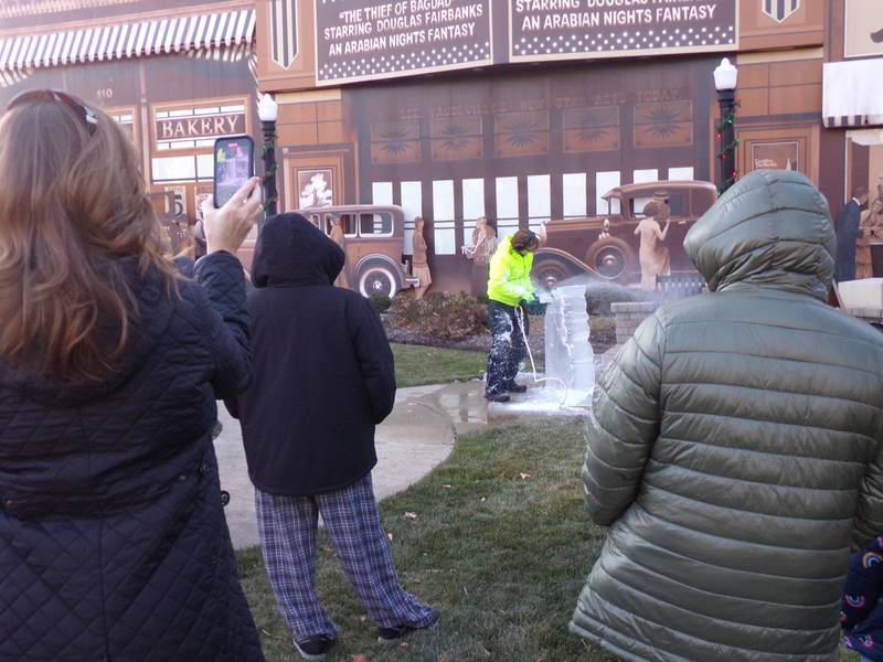 Spectators record the ice sculpture demonstration Saturday, Nov. 25, 2023, at Heritage Park in Streator during the Keeping Christmas Close to Home celebration.