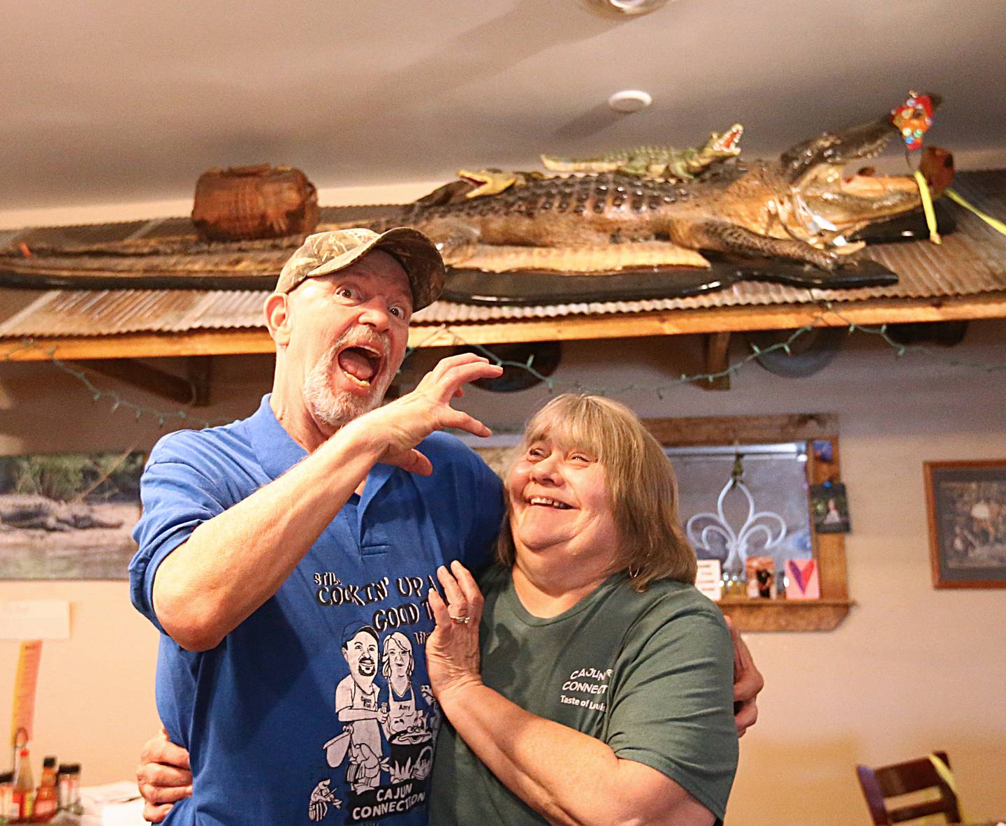 Cajun Connection owners Ron McFarlain and his wife Amy, pose for a photo with their alligator inside their restaurant on Wed. Aug. 24, 2022.  After 28 years in business the Cajun Connection is closing in Utica.