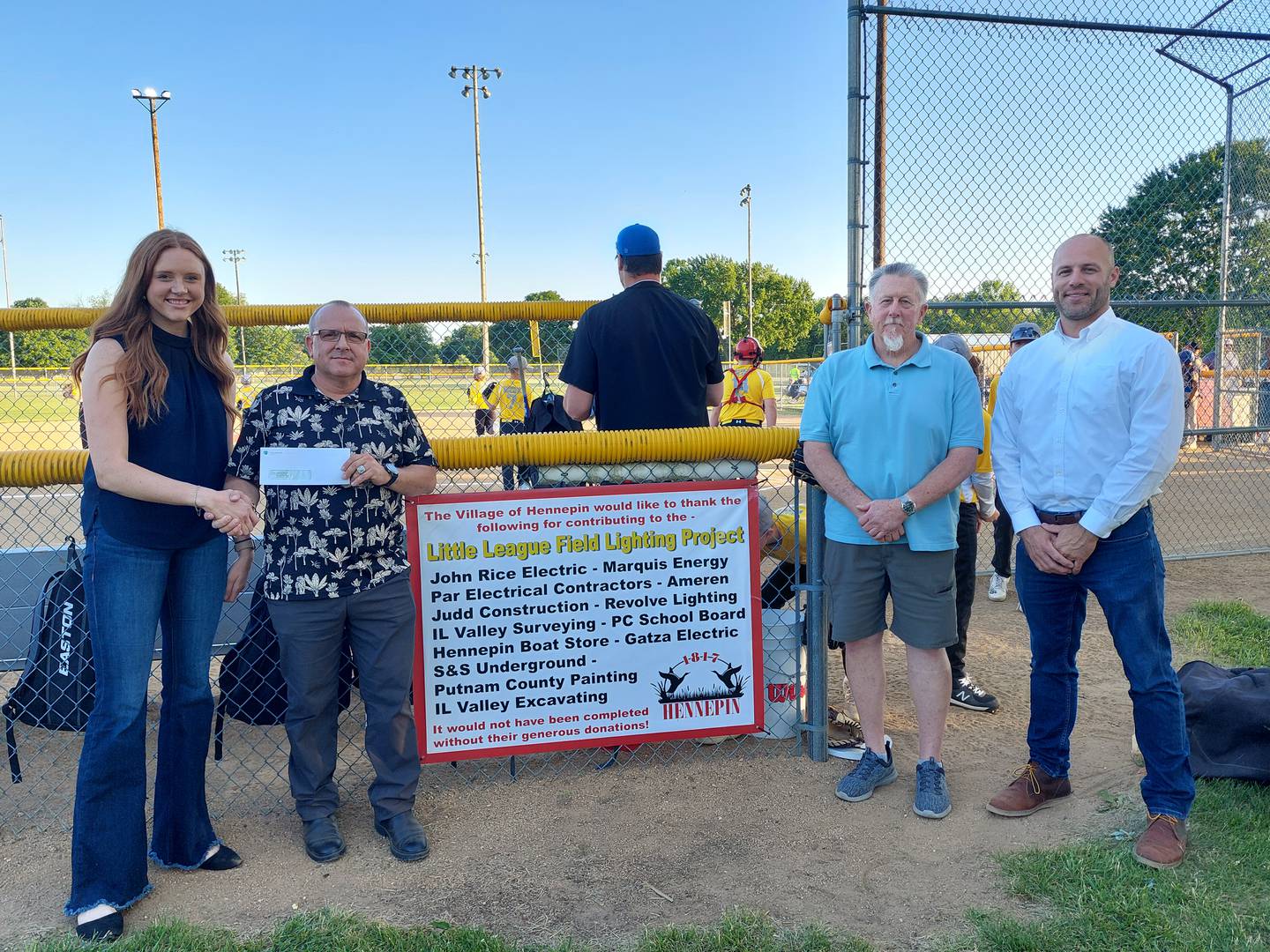 (From left) Allison Schwingle, of Marquis Energy; Quentin Buffington; Kevin Coleman, Hennepin village president; and Drew Schlumpf, of Marquis Energy pose for a check presentation Wednesday, May 22, 2024. Marquis Energy donated $10,000 for the Hennepin Little League field's lights.