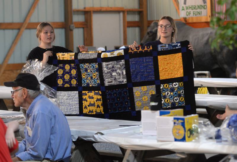 Two Oregon FFA members display one of two handmade quilts that were actioned during during the Oregon-Mt. Morris FFA alumni pork chop dinner and auction fundraiser at the Ogle County Fairgrounds on Saturday, June 8, 2024.