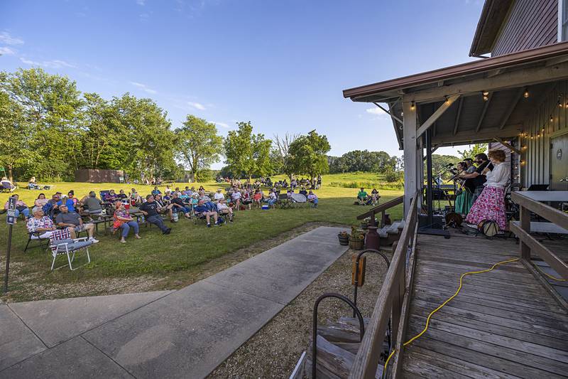 A crowd gathers on the lawn of the grist mill at Franklin Creek State Park to listen to music Saturday, June 22, 2024 for a summer solstice celebration and fundraiser for the park.