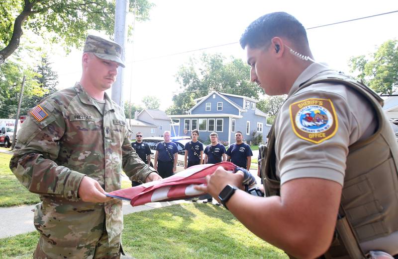 Army Pvt. Damien M. Presthus and La Salle County Sheriff's deputy and former United States Marine Johnny Godnia unfold a flag during a 9/11 Memorial Service on Wednesday, Sept. 11, 2024 at Circuit Breaker School in Peru. Firefighters police officers and paramedics from La Salle, Peru, and Hennepin participated in the memorial service.