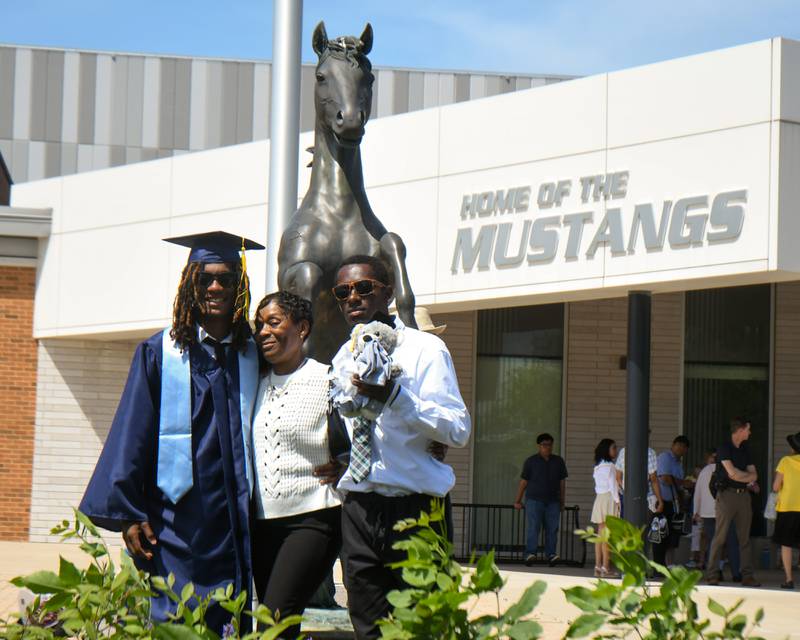 Downers Grove South graduate Damarius Jevon Davis along with Melanie Danise Moore, mom, and Darius Jovan Davis, brother, pose for a photo in front of the Mustang statue outside Downers Grove South High School on Sunday May 19, 2024.