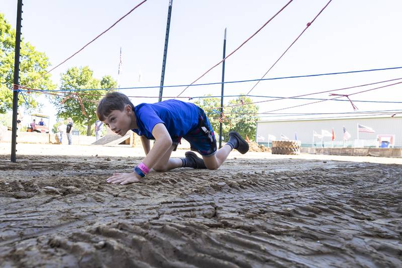 Trent Jordan, 11, of Chadwick crawls under an obstacle Saturday, August 12, 2023 while competing in the Ninja Farmer contest at the Carroll County Fair.