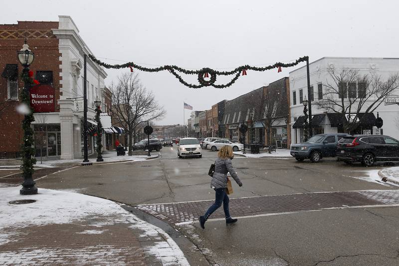 A woman dashes across North Williams Street in downtown Crystal Lake as the snow begins to fall Thursday, Dec. 22, 2022.