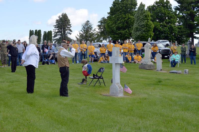 Veterans of Foreign Wars Post 8455 Auxiliary member Julie Young, left, stands next to VFW Post 8455 Commander Max Snook as he salutes the grave in Fairmount Cemetery dedicated to all the unknown soldiers after hanging a wreath in their honor during Polo's Memorial Day ceremony on Monday, May 27, 2024.