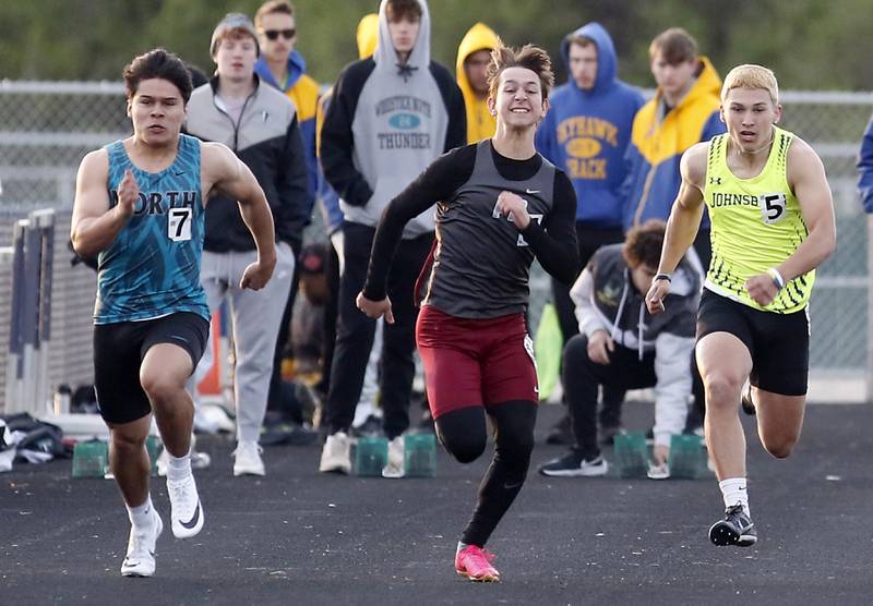 Woodstock North’s Mark Duenas, Prairie Ridge’s Eli Shoufer, and Johnsburg’s Nick LoPresti compete in the100 meter dash Friday, April 21, 2023, during the McHenry County Track and Field Meet at Cary-Grove High School.