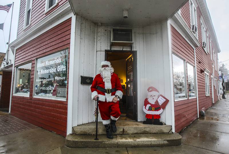 Despite the rain Santa Claus was outside Adam's Memorials & Memorable Gifts in McHenry greeting customers during Sunday's Christmas Walk in downtown McHenry November 17, 2013. The event featured shopping,  pony rides and horse-pulled wagon rides along with complimentary trolley rides, costumed characters strolling up and down the streets, carolers and more.