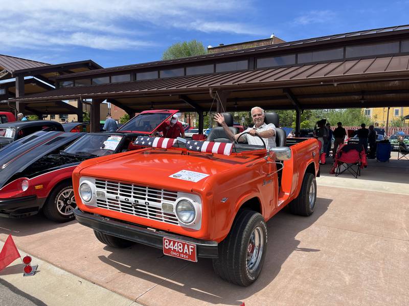 Owner, Paul K Le Tang of Rock Falls, waves from his 1966 orange Ford Bronco at the 11th annual car show on Sunday, May 5, at the Sterling Marketplace.