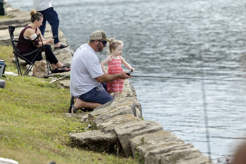 Ella Dempsey, 3, helps dad Mark reel in in the line Saturday, July 1, 2023 during the Elk’s Club Fishing Derby in Dixon.