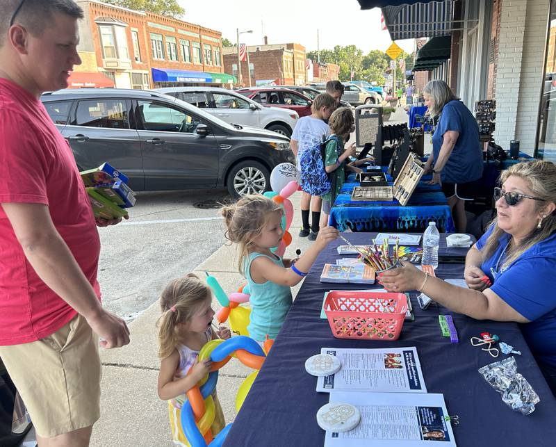 Anna and Leah Larson, 4 and 2, of Prophetstown, pick up school supplies at one of the booths as their dad, Luke watches, during Prophetstown's Fourth Friday on Friday, July 26, 2024.