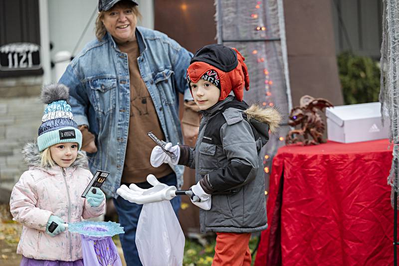 Harley, 3, and Colton Lenert, 6, grab candy from Mary Lally Tuesday, Oct. 31, 2023 while trick or treating for Halloween.