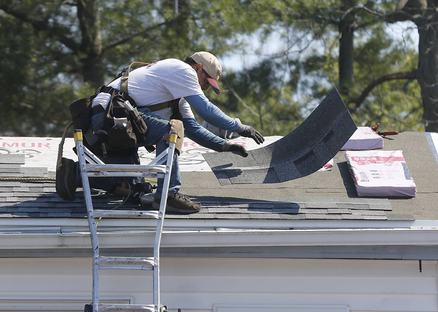 A worker from Feldco replaces the roof of U.S. Army veteran Robin Waltrip’s home in Island Lake on Monday April 8, 2024, as part of the Owens Corning Roof Deployment Project. The Owens Corning Foundation is donating roofing materials and Feldco is donating the labor.