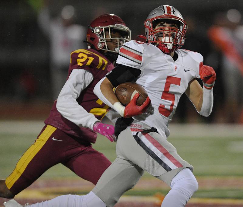 Palatine’s Thomas Coroneos tries to outrun Schaumburg’s Takumi Fred with the opening kickoff in a football game in Schaumburg on Friday, October 14, 2022.