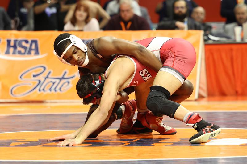 Joliet Catholic’s Jason Hampton works over Maine South’s Teddy Flores in the 120-pound Class 3A state championship match on Saturday, Feb. 17th, 2024 in Champaign.