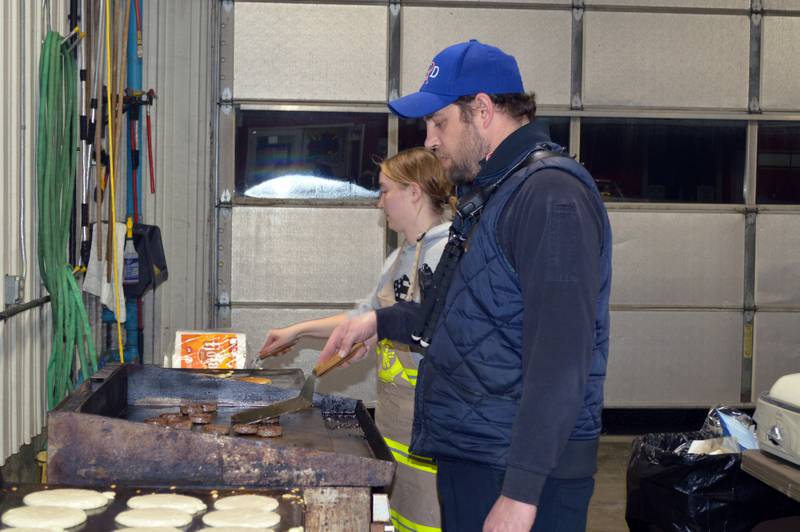 Leaf River Fire Protection District firefighter Sean Smith, foreground, and EMT Olivia Stranberg cook sausage and pancakes on Feb. 25, 2023, during the annual Leaf River Firemen's Pancake Supper. A little over 700 people attended the fundraiser at the Leaf River fire station, raising $2,050.