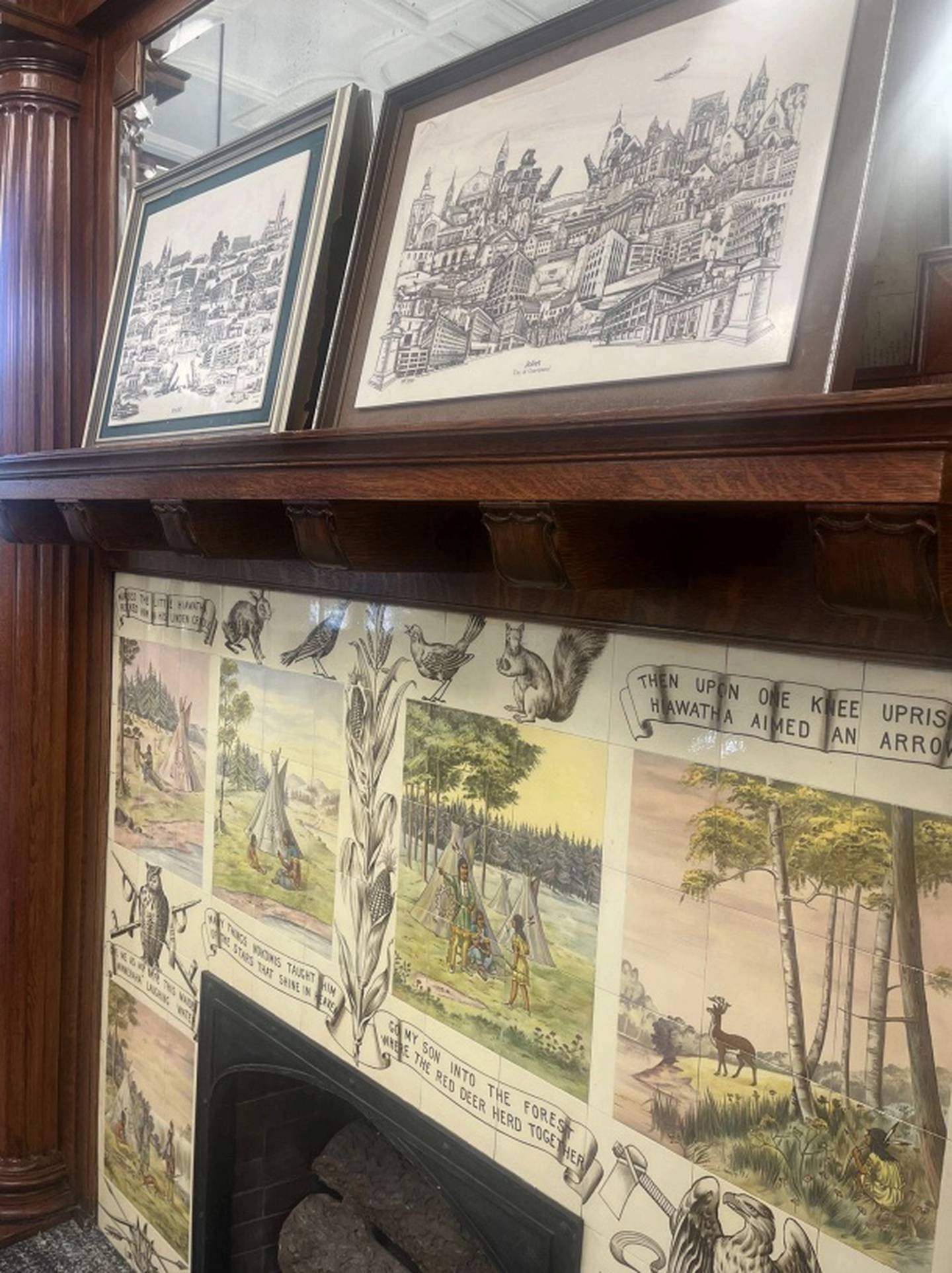 The fireplace in the Local History section of the Joliet Public Library Ottawa Street Branch, with Hiawatha tiles and Joliet art displayed on the mantle.