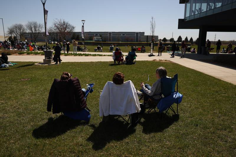 A group of ladies watch the eclipse on the lawn at the Joliet Junior College solar eclipse viewing event on Monday, April 8, 2024 in Joliet.
