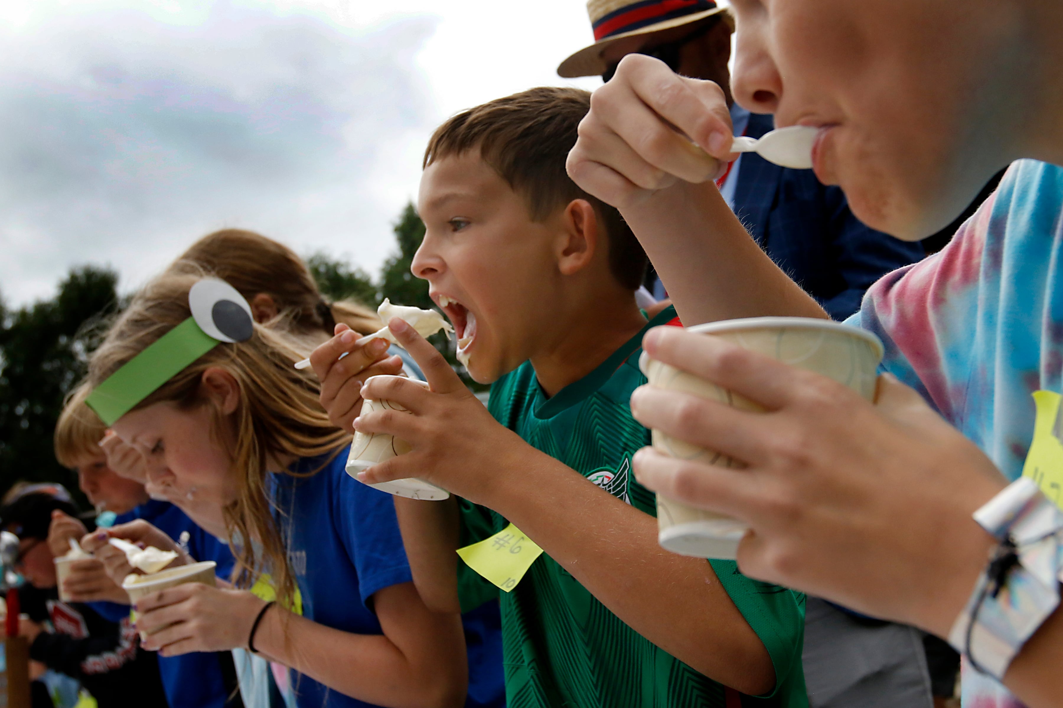 Luke Ridley (center) shovels ice cream into his mouth on his way to winning his round of the Brain Freese Ice Cream Eatin’ Contest during the Ice Cream Fest on Friday, Aug. 9, 2024, at Crystal Lake’s Main Beach.  The second annual event featured music, ice cream venders and the ice cream eating contest.