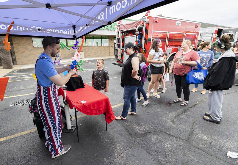 Balloon artist Chris Busker ties up a poodle for Nina and Liam Lyster, 8, Saturday, June 8, 2024 in Dixon. Busker was brought in for the entertainment by Discover Dixon.