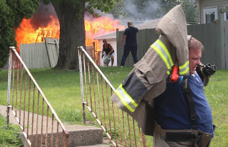 La Salle firefighter Brian Zeller throws on his bunker gear after getting out of his vehicle to battle a garage fire in the 800 block of Lafayette Street on Monday, July 22, 2024. The fire began just before 1p.m. La Salle Fire and EMS along with Peru Fire department responded to the call.