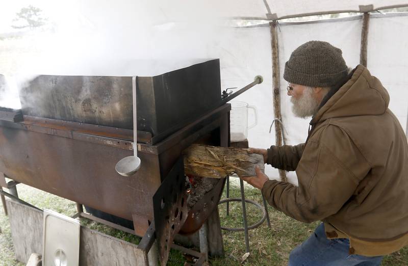 Chuck Howenstine adds a log to the fire as he cooks maple syrup on Thursday, March 9, 2023, at the Pioneer Tree Farm near McHenry. He has been collecting sap for most of his adult life to make maple syrup that he gives away.