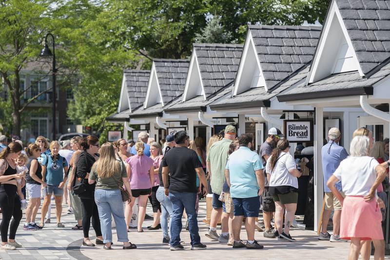 Shoppers explore the new collection of tiny shops at the grand opening and ribbon cutting of the new McHenry Riverwalk Shoppes in downtown McHenry on Friday, July 21, 2023.