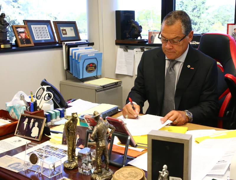 La Salle County State's Attorney Joe Navarro signs a document behind his desk in an Augusts file photo at the La Salle County Governmental Complex in Ottawa.