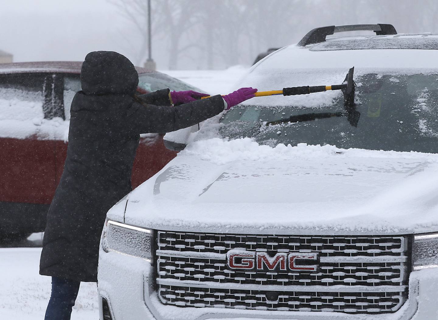 Teacher Leah Pinkowski cleans the windows of her car Thursday, Feb. 16, 2023, at Richmond-Burton Community High School in Richmond, after a winter storm moved through McHenry County creating hazardous driving conditions.