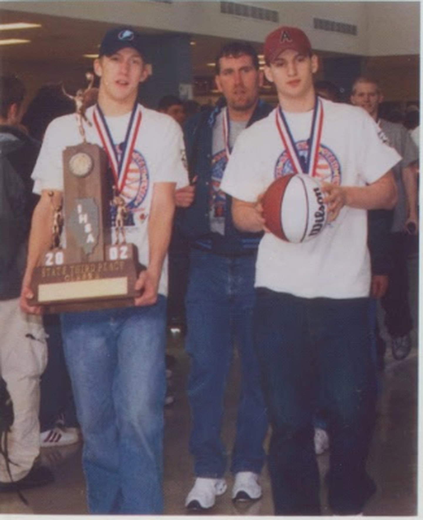 Bureau Valley captains Phil Endress (left) and Adam Gutshall and coach Brad Bickett proudly carry in the third-place trophy from the 2001-02 IHSA State Basketball Tournament.